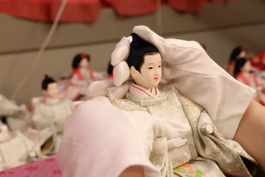 Artisan carefully handling a handcrafted Hina doll at Fujiki Crafts, showcasing traditional Japanese craftsmanship.