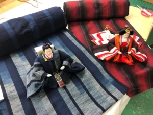 Hina dolls dressed in traditional textiles displayed by Fujiki Crafts, showcasing meticulous Japanese craftsmanship.