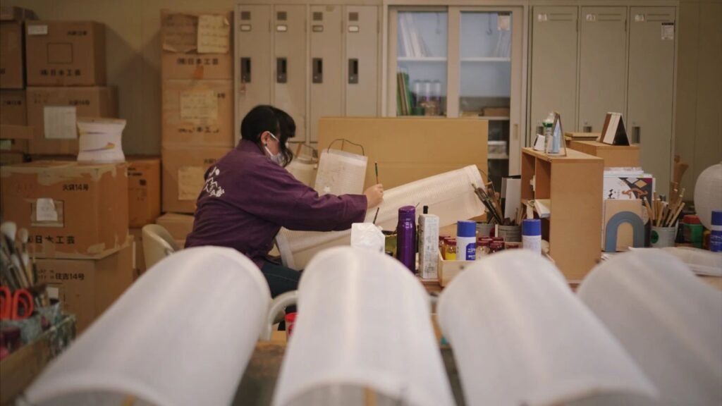 A person crafts in a workshop surrounded by materials.