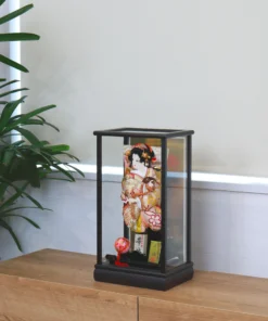 Hagoita paddle with elegant kimono-clad female figure, with gold and red embroidery, displayed on a black lacquered base and display case with decorative ball. Wholesale by Fujiki Crafts.