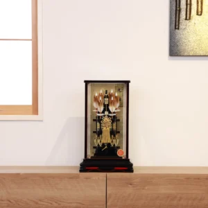Japanese Hamaya arrow display with gold cord and tassel in black lacquer case, set against gold background with feathered arrows and symbolic ornaments. Wholesale by Fujiki Crafts.