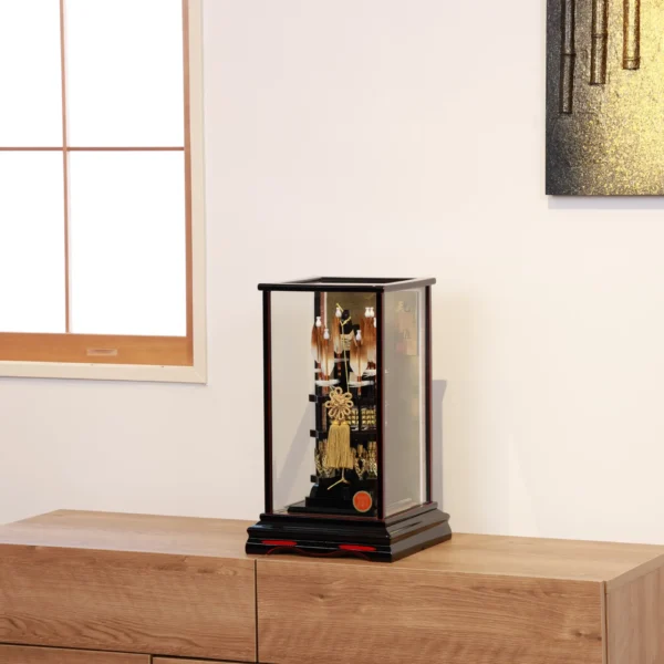 Japanese Hamaya arrow display with gold cord and tassel in black lacquer case, set against gold background with feathered arrows and symbolic ornaments. Wholesale by Fujiki Crafts.