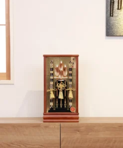 Japanese Hamaya arrow display with gold cord tassels and feathered arrows in a wooden frame case, set against a gold textured backdrop. Wholesale by Fujiki Crafts.