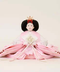 Japanese Hina Empress doll in soft pink and white kimono, holding pearl-decorated fan. Wholesale by Fujiki Crafts.