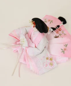 Japanese Hina Empress doll in soft pink and white kimono, holding pearl-decorated fan. Wholesale by Fujiki Crafts.