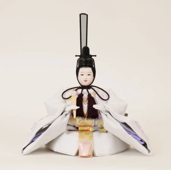 Emperor Hina doll in white patterned kimono with gold and purple accents, holding a ceremonial baton. Wholesale by Fujiki Crafts.
