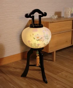 Handcrafted Japanese Bonbori-style lantern with floral washi paper shade on black lacquered wood stand, featuring pastel flowers and golden tassel. Wholesale by Fujiki Crafts.