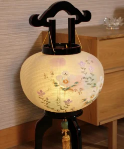 Handcrafted Japanese Bonbori-style lantern with floral washi paper shade on black lacquered wood stand, featuring pastel flowers and golden tassel. Wholesale by Fujiki Crafts.