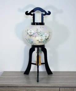 Handcrafted Japanese Bonbori-style lantern with floral washi paper shade on black lacquered wood stand, featuring pastel flowers and golden tassel. Wholesale by Fujiki Crafts.