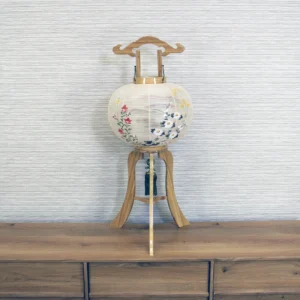 Handcrafted Japanese Bonbori lantern with washi paper shade, featuring hand-painted red spider lilies, wild daisies, and yellow rapeseed flowers on a natural wood stand. Wholesale by Fujiki Crafts.