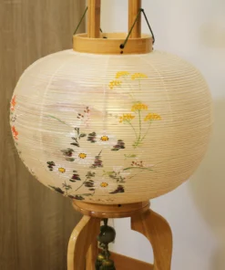 Handcrafted Japanese Bonbori lantern with washi paper shade, featuring hand-painted red spider lilies, wild daisies, and yellow rapeseed flowers on a natural wood stand. Wholesale by Fujiki Crafts.