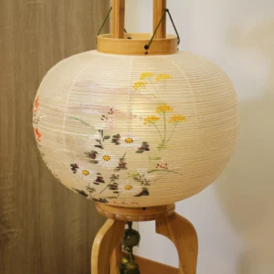 Handcrafted Japanese Bonbori lantern with washi paper shade, featuring hand-painted red spider lilies, wild daisies, and yellow rapeseed flowers on a natural wood stand. Wholesale by Fujiki Crafts.