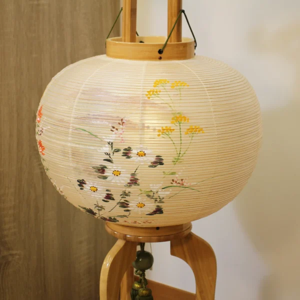 Handcrafted Japanese Bonbori lantern with washi paper shade, featuring hand-painted red spider lilies, wild daisies, and yellow rapeseed flowers on a natural wood stand. Wholesale by Fujiki Crafts.