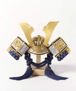 Japanese Kabuto helmet display with gold crest and silk thread navy strap on red lacquered base, featuring folding screen, miniature sword, and decorative arrows. Wholesale by Fujiki Crafts.