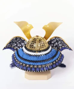 Japanese Kabuto helmet display with gold crest and silk thread navy strap on red lacquered base, featuring folding screen, miniature sword, and decorative arrows. Wholesale by Fujiki Crafts.