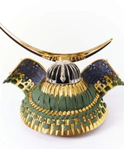 Japanese Kabuto helmet with gold crescent crest and green cord accents, set in a round wooden frame with gold patterned background. Wholesale by Fujiki Crafts.