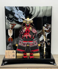 Handcrafted Japanese Samurai armor set in red and black, displayed with dragon and tiger backdrop. Wholesale by Fujiki Crafts