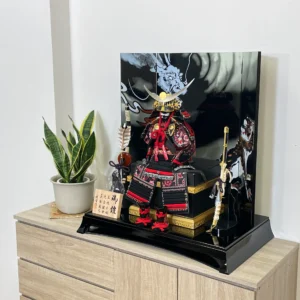 Handcrafted Japanese Samurai armor set in red and black, displayed with dragon and tiger backdrop. Wholesale by Fujiki Crafts