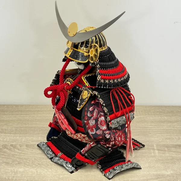 Handcrafted Japanese Samurai armor set in red and black, displayed with dragon and tiger backdrop. Wholesale by Fujiki Crafts