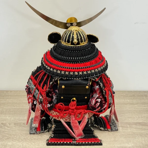 Handcrafted Japanese Samurai armor set in red and black, displayed with dragon and tiger backdrop. Wholesale by Fujiki Crafts