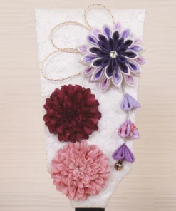 Handcrafted Japanese Hagoita paddle in display case with soft pink and purple flowers, set on wooden base with Yuubi nameplate. Wholesale by Fujiki Crafts.