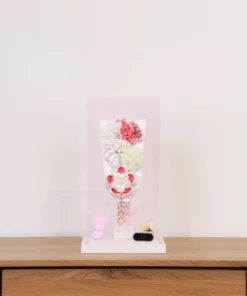 Handcrafted Japanese Hagoita paddle in white and soft pink tones, adorned with large fabric flowers and decorative beads. Set in a pink-edged clear acrylic case with a white base. Wholesale by Fujiki Crafts.