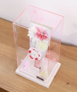 Handcrafted Japanese Hagoita paddle in white and soft pink tones, adorned with large fabric flowers and decorative beads. Set in a pink-edged clear acrylic case with a white base. Wholesale by Fujiki Crafts.