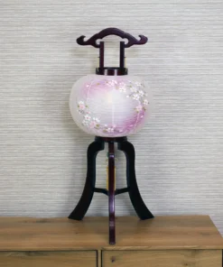 Handcrafted Japanese Chōchin lantern with cherry blossom design on white and lavender washi paper, displayed on wooden base. Wholesale by Fujiki Crafts.