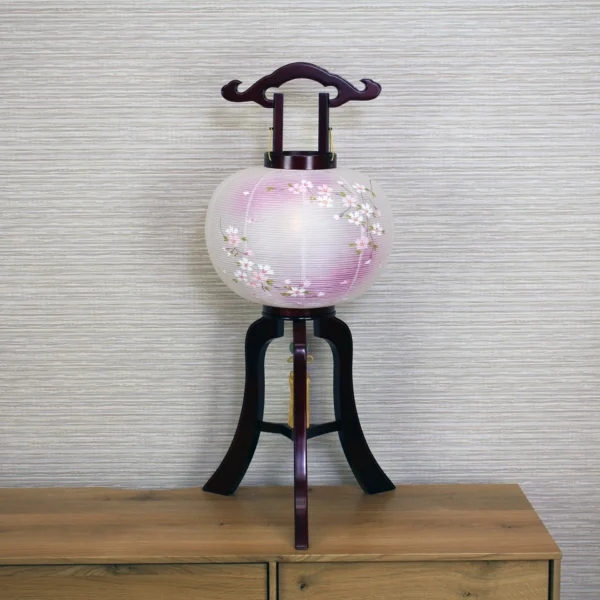 Handcrafted Japanese Chōchin lantern with cherry blossom design on white and lavender washi paper, displayed on wooden base. Wholesale by Fujiki Crafts.