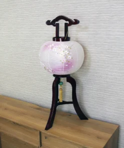 Handcrafted Japanese Chōchin lantern with cherry blossom design on white and lavender washi paper, displayed on wooden base. Wholesale by Fujiki Crafts.