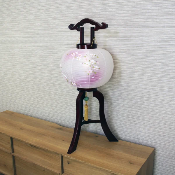 Handcrafted Japanese Chōchin lantern with cherry blossom design on white and lavender washi paper, displayed on wooden base. Wholesale by Fujiki Crafts.
