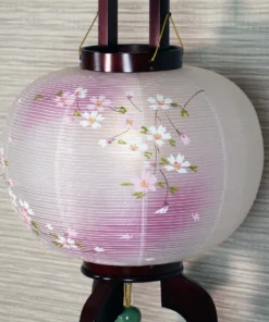 Handcrafted Japanese Chōchin lantern with cherry blossom design on white and lavender washi paper, displayed on wooden base. Wholesale by Fujiki Crafts.