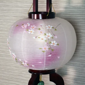 Handcrafted Japanese Chōchin lantern with cherry blossom design on white and lavender washi paper, displayed on wooden base. Wholesale by Fujiki Crafts.