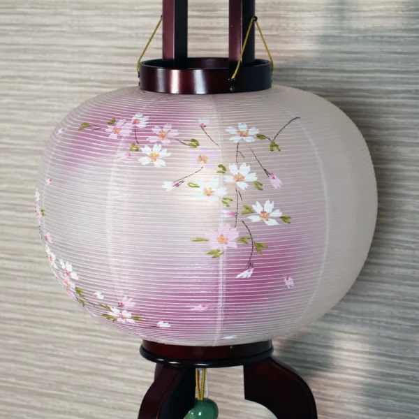 Handcrafted Japanese Chōchin lantern with cherry blossom design on white and lavender washi paper, displayed on wooden base. Wholesale by Fujiki Crafts.