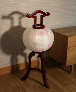 Handcrafted Japanese Chōchin lantern with cherry blossom design on white and lavender washi paper, displayed on wooden base. Wholesale by Fujiki Crafts.