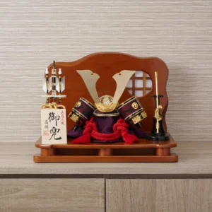 Handcrafted Japanese kabuto samurai helmet display with red cord and gold accents, set on a wooden stand with katana and arrows. Wholesale by Fujiki Crafts.
