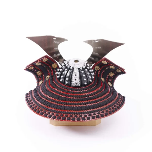 Traditional Kabuto samurai helmet with silver crest, mounted on a dark wood base, flanked by miniature sword and arrow display. Wholesale by Fujiki Crafts.
