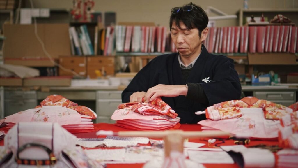 Person folding colorful garments in a workshop setting.