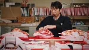 Person folding colorful garments in a workshop setting.