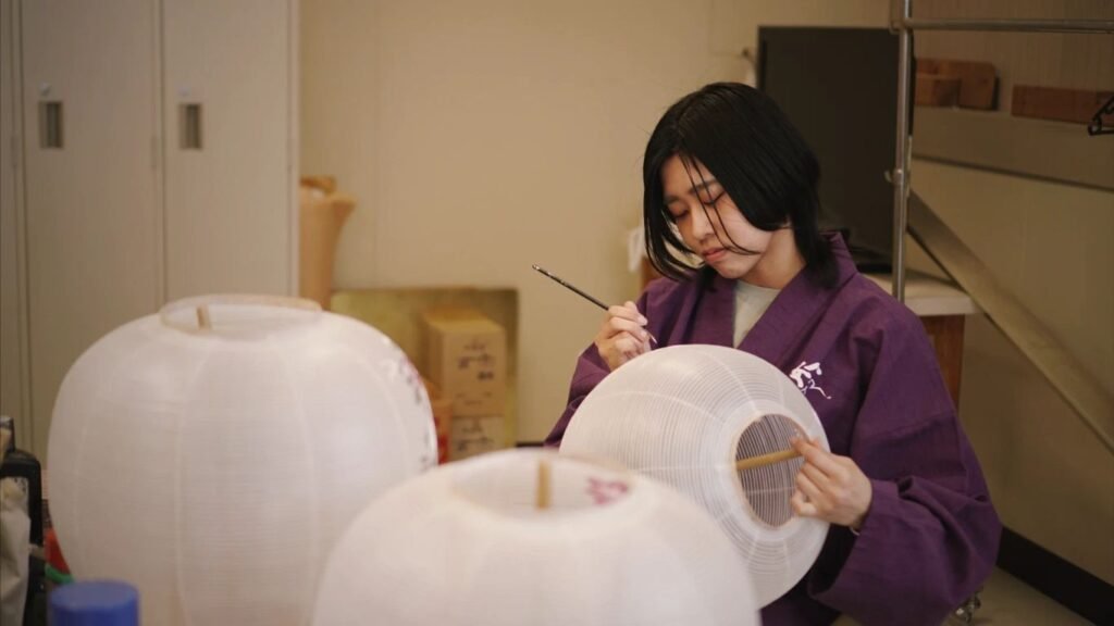 Person painting traditional lanterns in a workshop setting.