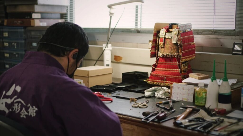 A person works on traditional armor in a workshop.