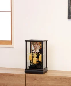 Decorative Japanese Hamaya arrow display encased in glass, featuring golden tassels, black lacquered base, and symbolic arrows with feathers, used for protection and blessings. Wholesale by Fujiki Crafts.
