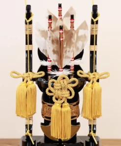 Decorative Japanese Hamaya arrow display encased in glass, featuring golden tassels, black lacquered base, and symbolic arrows with feathers, used for protection and blessings. Wholesale by Fujiki Crafts.