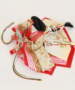 Empress Hina Doll wearing a vivid red kimono with gold detailing, holding a colorful decorative folding fan, and styled with a traditional court hairstyle topped with a red crown. Wholesale by Fujiki Crafts.