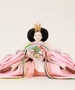 Close-up of traditional Japanese Empress Hina Doll in layered pink kimono, holding a colorful fan with gold and red kanzashi crown on a white background. Wholesale by Fujiki Crafts.
