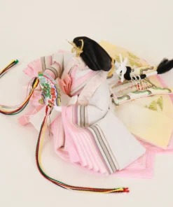 Close-up of traditional Japanese Empress Hina Doll in layered pink kimono, holding a colorful fan with gold and red kanzashi crown on a white background. Wholesale by Fujiki Crafts.