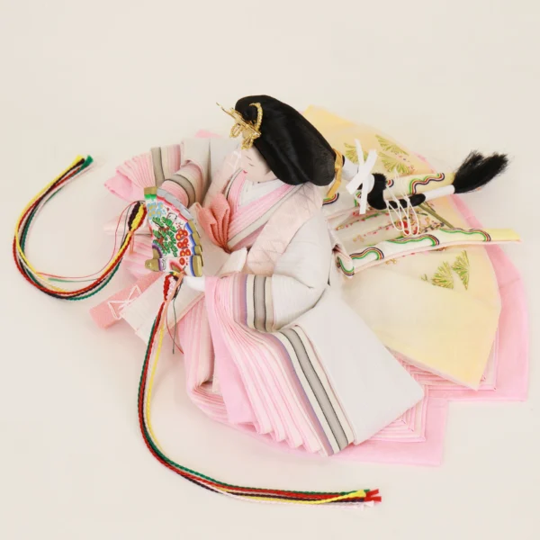 Close-up of traditional Japanese Empress Hina Doll in layered pink kimono, holding a colorful fan with gold and red kanzashi crown on a white background. Wholesale by Fujiki Crafts.