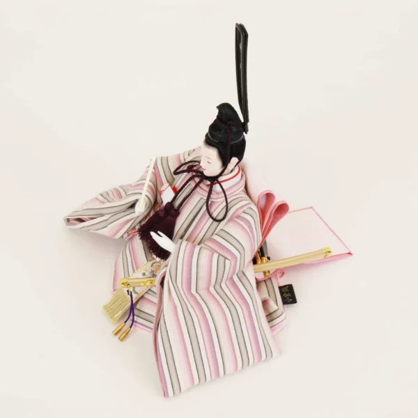 Close-up of Japanese Emperor Hina Doll in striped pastel kimono with black hat and fan, seated in formal pose on white background. Wholesale by Fujiki Crafts.